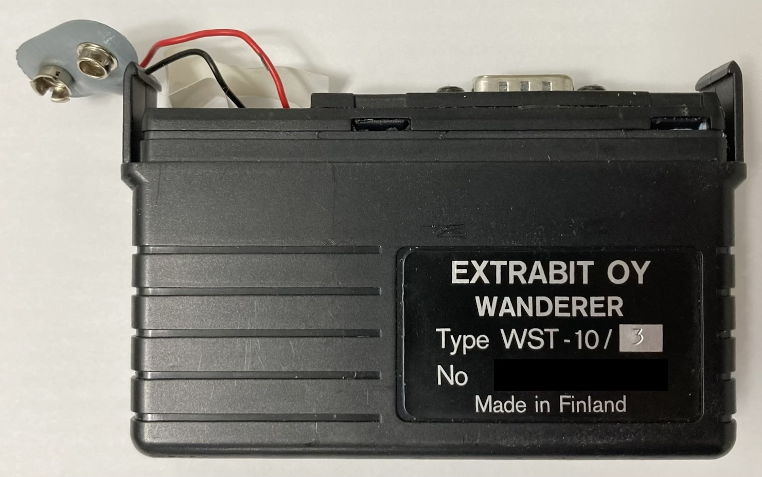 The Wanderer with its top piece off. Visible: the battery connector, the white string for pulling the battery out, and the DE-9 serial port.